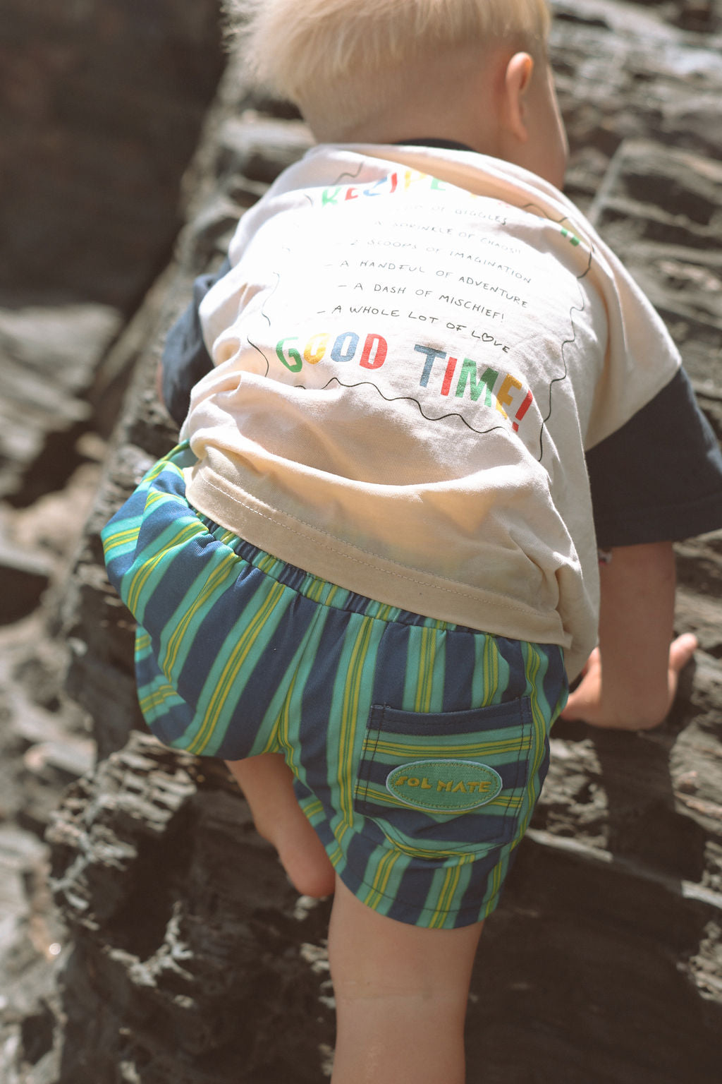 Child wearing blue, green and yellow striped shorts.