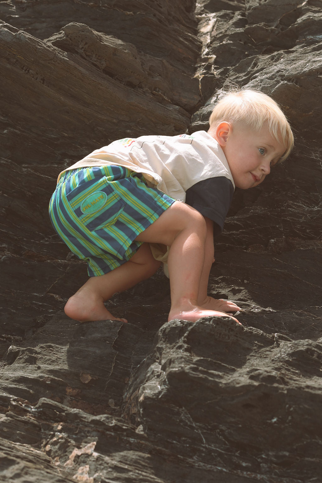 Child wearing blue, green and yellow striped shorts.