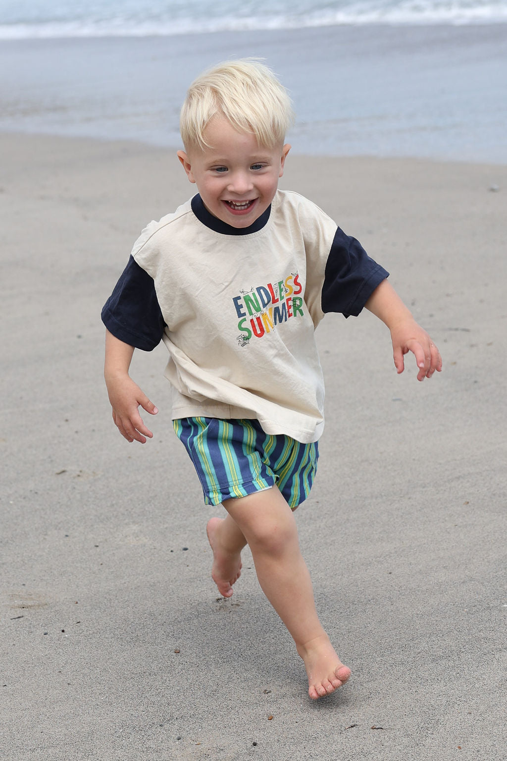 Child wearing blue, green and yellow striped shorts.