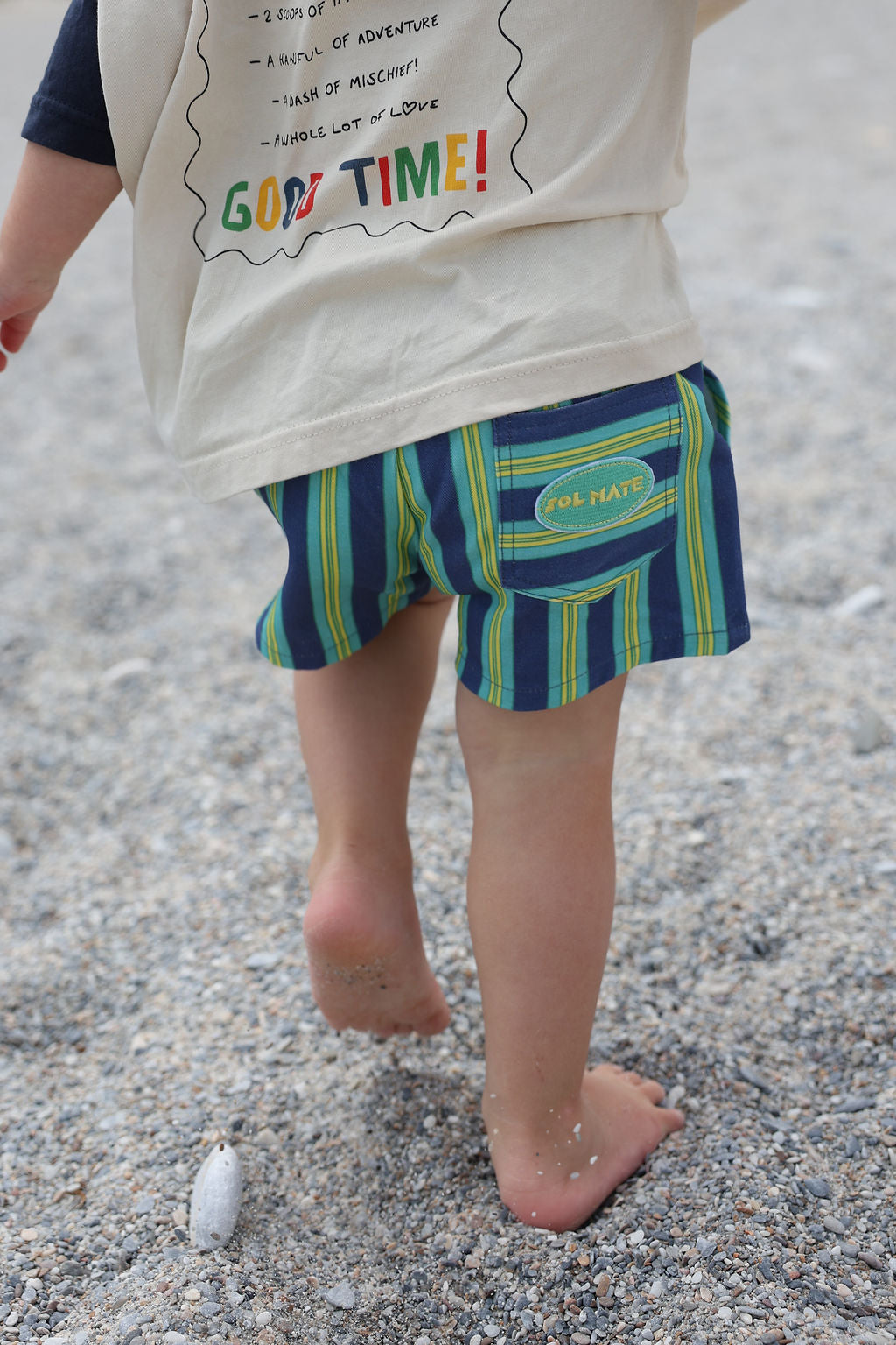 Child wearing blue, green and yellow striped shorts.
