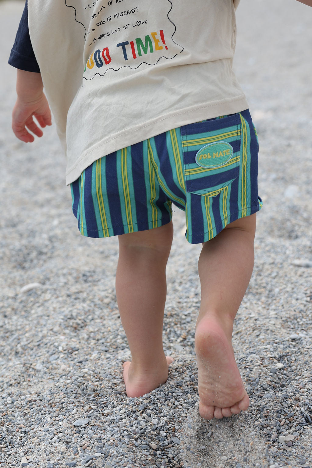 Child wearing blue, green and yellow striped shorts.