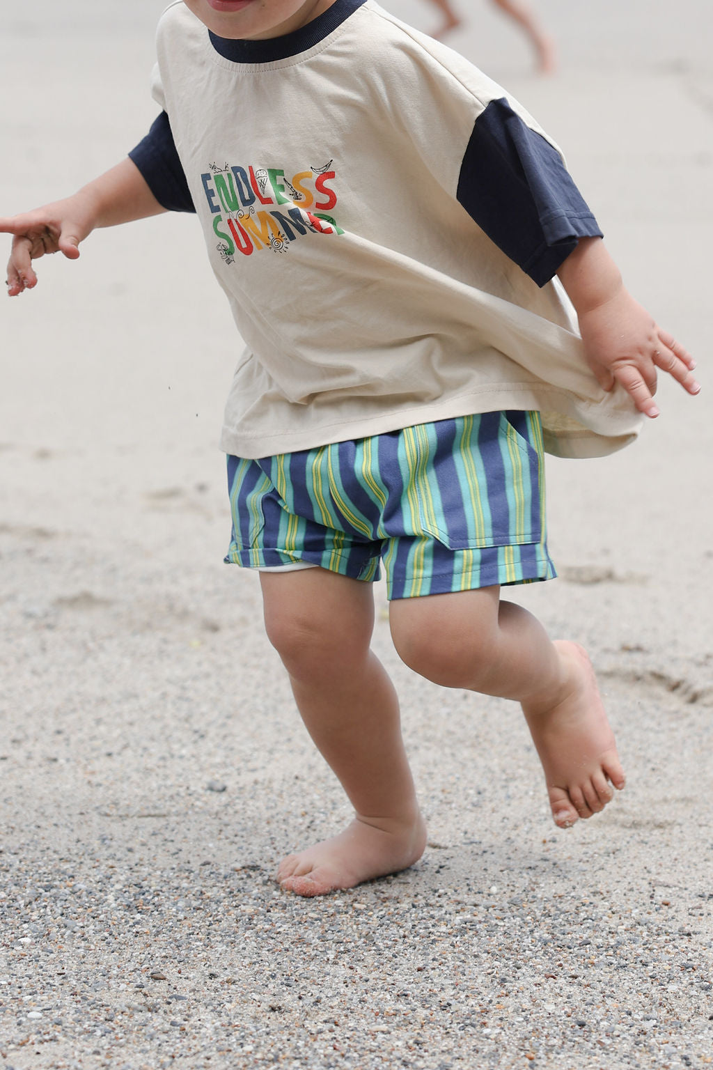 Child wearing blue, green and yellow striped shorts.