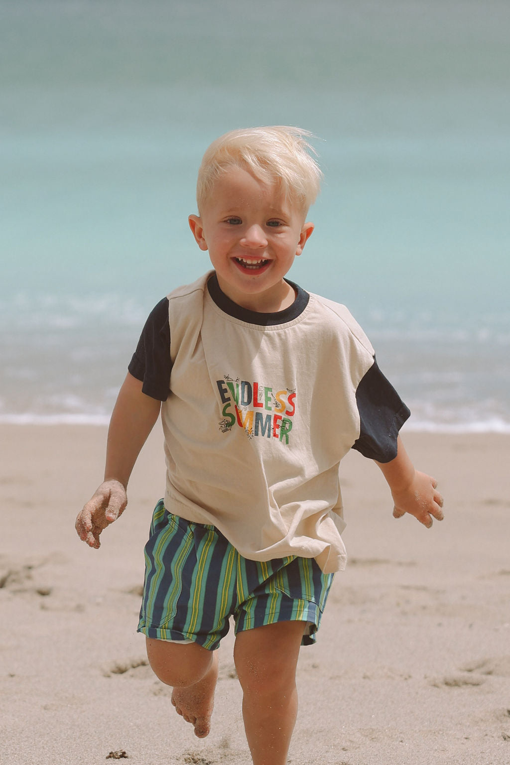 Child wearing blue, green and yellow striped shorts.