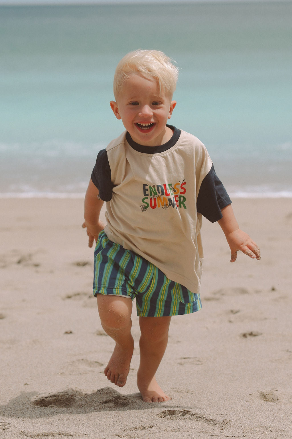Child wearing blue, green and yellow striped shorts.