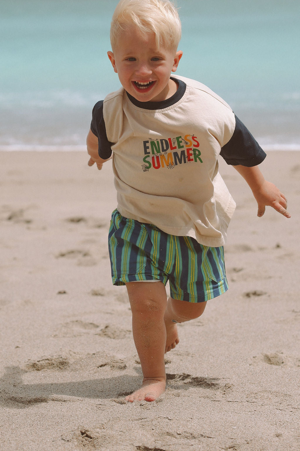 Child wearing blue, green and yellow striped shorts.