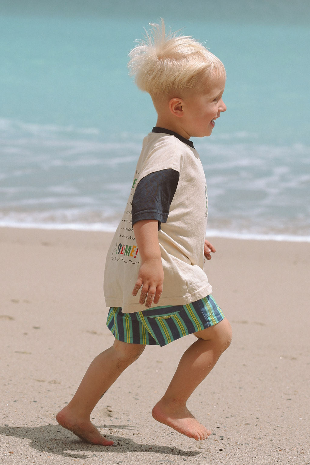 Child wearing blue, green and yellow striped shorts.