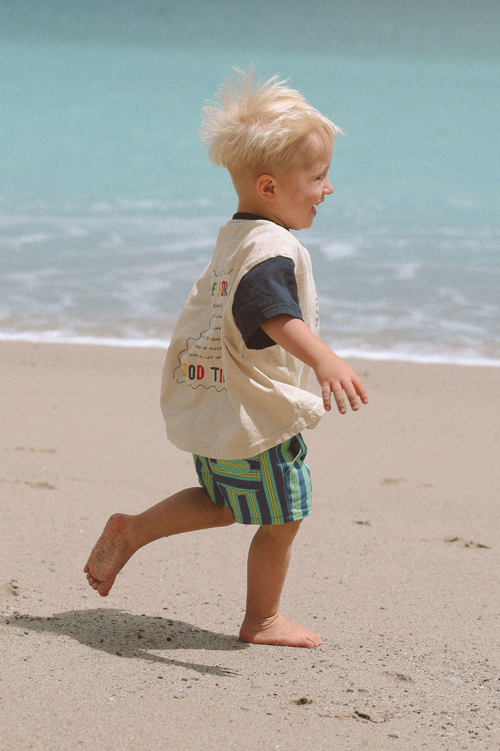 Child wearing blue, green and yellow striped shorts.