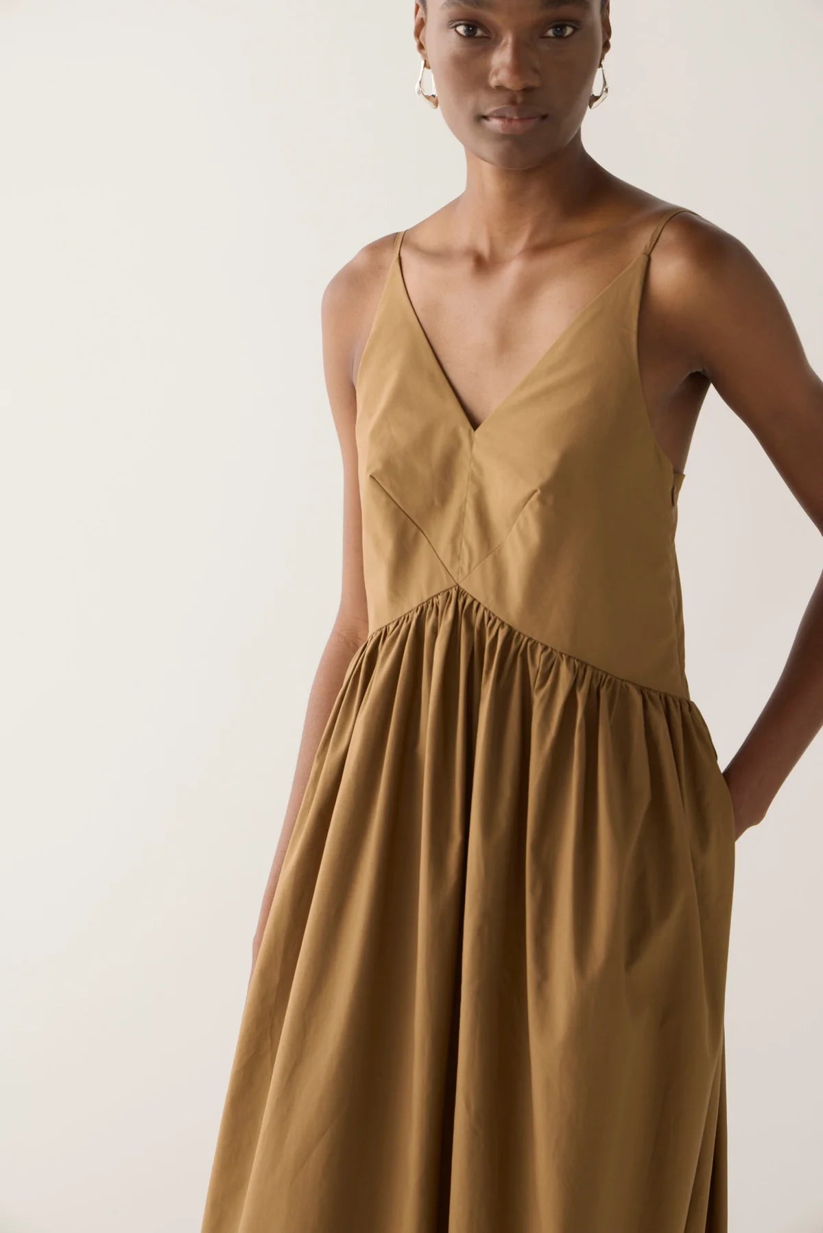 Close up of front bodice of model wearing Amanda dress from Foemina. Cocoa cotton tencel spaghetti strap dress with gathering at bodice seam, adjustable straps, side seam pockets and bodice seam details