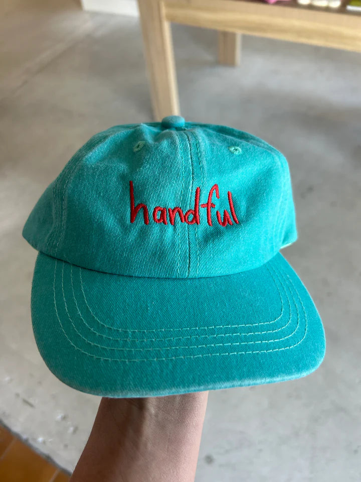 Aqua coloured cotton cap with “handful” text in red