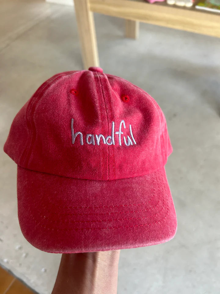 Red coloured cotton cap with “handful” text in blue