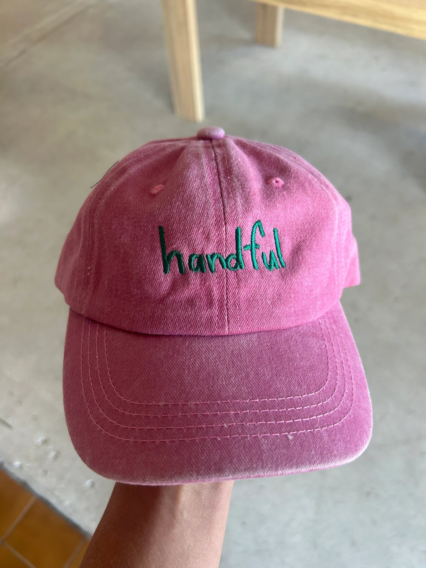 Pink coloured cotton cap with “handful” text in green