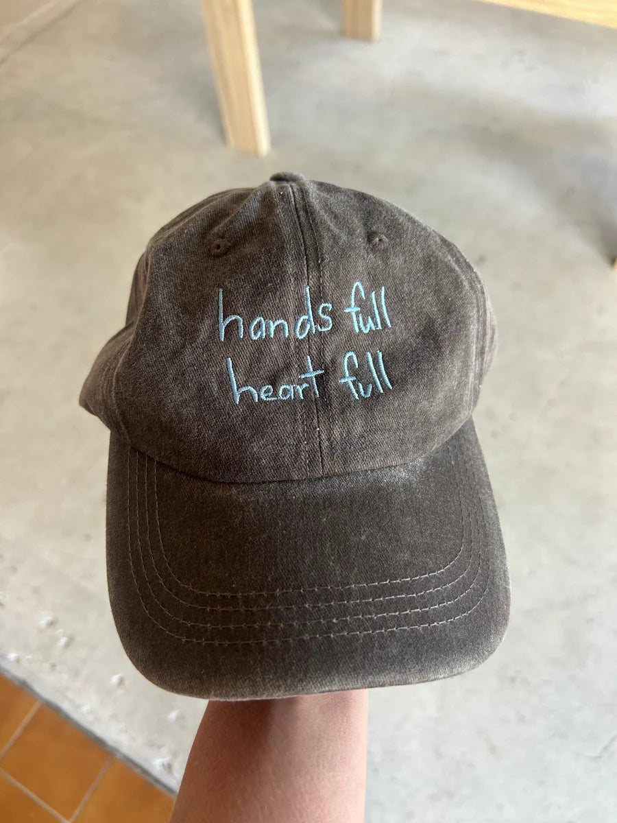 Grey cap with blue “hands full heart full” text made from cotton