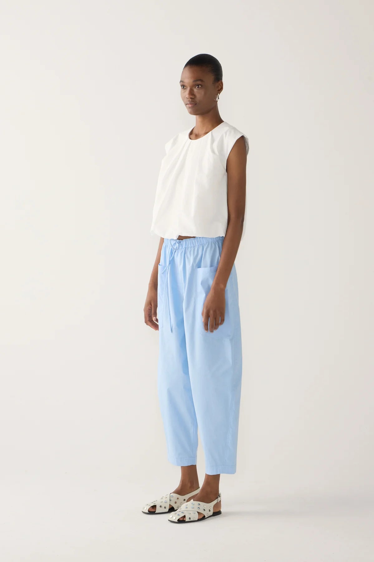  Model wearing chambray cropped barrel leg organic cotton poplin pants with a drawstring waist and front patch pockets