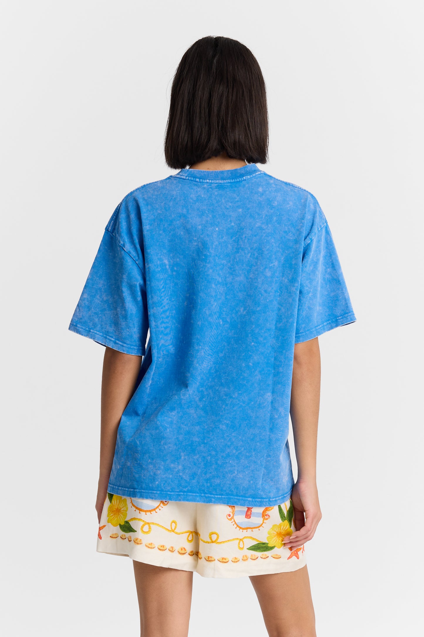 Person wearing a blue t-shirt and colorful shorts on a white background