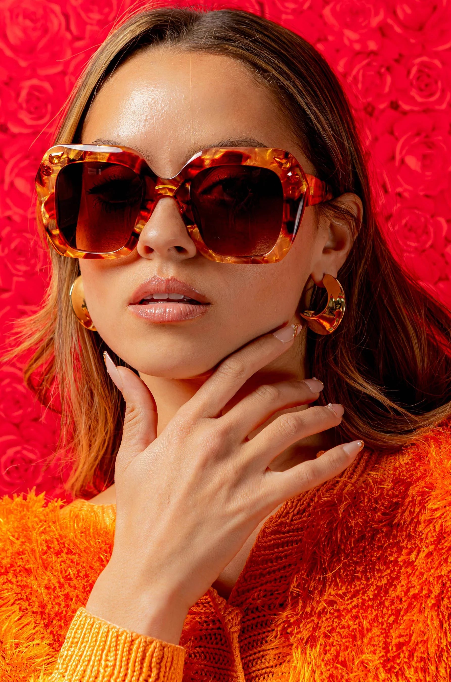 Woman wearing oversized red and apricot sunglasses with crystals 